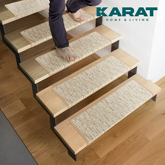 Stufenmatte Geneva - 65 x 23,5 cm, Beige, Rechteck - Aufnahme von Treppenstufen mit Teppichauflagen, die mit dem "KARAT HOME & LIVING"-Logo versehen sind, für ein stilvolles Zuhause.