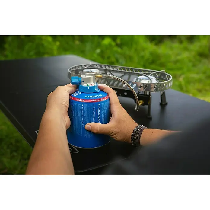 Campingaz Campingkocher Camp & Trek Twin Connect CV - Anzahl Brenner: 2 Stk., 2 kW - Nahaufnahme einer Hand, die eine blaue Campingaz-Gasflasche an einen Kocher anschließt, ideal für Outdoor-Abenteuer.