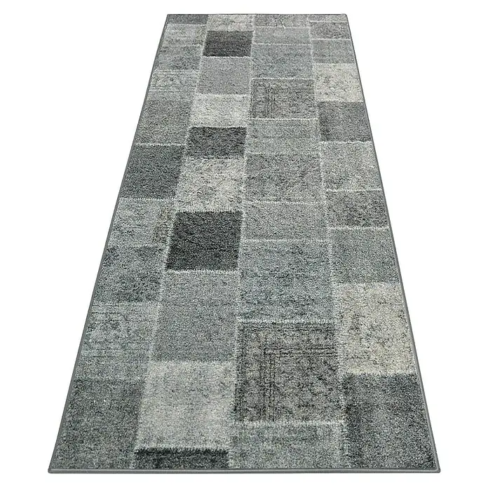 Teppichläufer Monsano - Anthrazit, 250 x 80 cm, 100 % Polyamid - Ein grauer Patchwork-Teppich mit verschiedenen Texturen und Farbtönen liegt auf einem dunklen Untergrund. Der Teppich wirkt modern und stilvoll.
