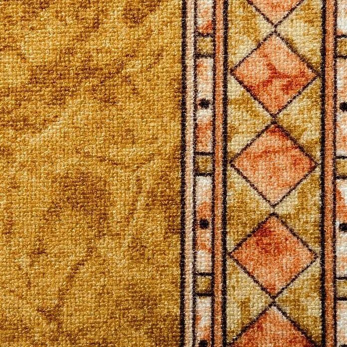 Teppichläufer Rügen - Beige, 500 x 80 cm, 100 % Polyamid - Nahaufnahme eines Teppichs mit goldenem Hintergrund und einem geometrischen Rautenmuster in Orange, Beige und Schwarz.