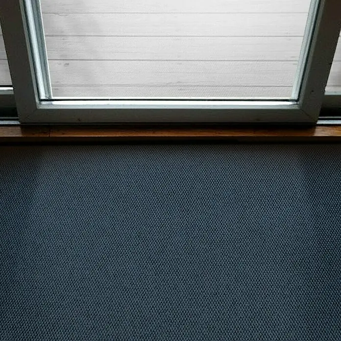 Schmutzfangmatte Hong Kong - Blau, 1.100 x 200 cm, 100 % Polypropylen - Nahaufnahme eines Fensters mit weißem Rahmen und Blick auf eine helle Holzoberfläche, darunter eine strukturierte, blaugraue Oberfläche.