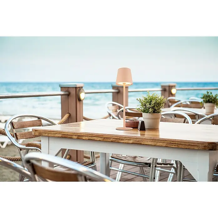 Globo LED-Tischleuchte Vannie - 3 W, Pfirsichfarben, Höhe: 360 mm, Durchmesser: 106 mm, IP44 - Tisch mit einer modernen, kabellosen Lampe auf einer Terrasse mit Meerblick.