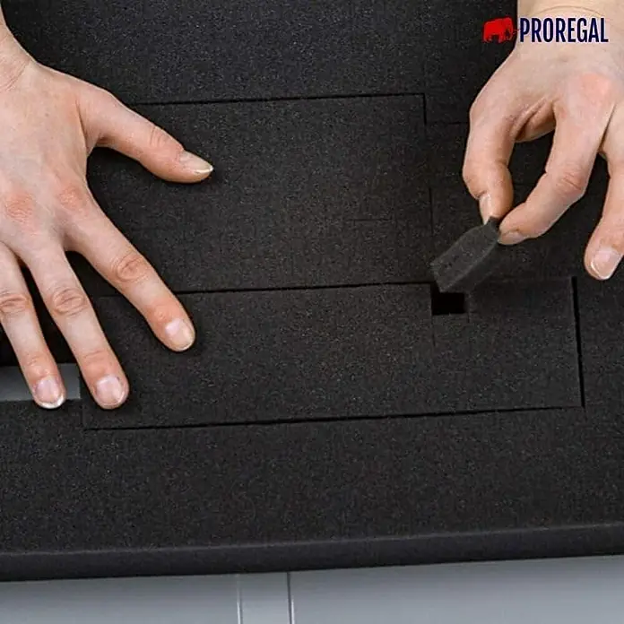Proregal Euroboxen-Set 5x Eurobox NextGen Portable mit Rasterschaumstoff & Schaumstoffeinlage - Kunststoff, Grau, 5 Stk. - Ein Foto zeigt das Entnehmen von Schaumstoffstücken aus einer maßgefertigten PROREGAL-Schaumstoffeinlage für eine individuelle Aufbewahrungslösung.