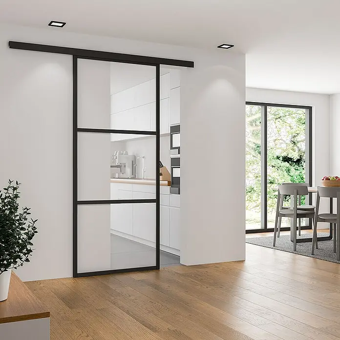 Inova Schiebetür-Komplettset Loft Klarglas Komplettset 3 Felder schwarz - 755 x 2.035 mm - Ein modernes Interieur zeigt eine elegante Schiebetür mit schwarzem Rahmen, die den Raum optisch trennt und gleichzeitig Licht durchlässt.