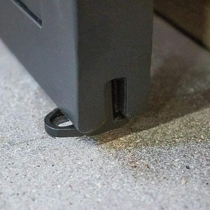 Inova Schiebetür-Komplettset Lofttür Komplettset Stahl Doppelflügelig - 2.050 x 2.150 mm - Nahaufnahme eines schwarzen Möbelstücks mit einem stilvollen Metallfuß auf einem grauen Untergrund. Das Möbelstück besticht durch schlichtes Design.