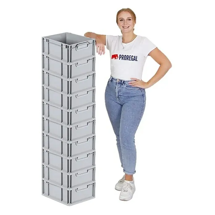 Proregal Euroboxen-Set 10x Eurobox NextGen Grip - L x B x H: 40 x 30 x 17 cm, Kunststoff, Grau, 10 Stk. - Eine Frau steht neben einem Stapel aus neun grauen Proregal-Kunststoffboxen mit Griffmulden. Die Boxen sind stapelbar und ideal für Lagerung und Organisation.