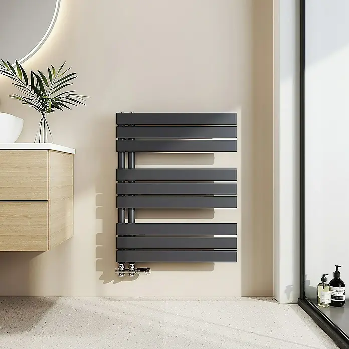 Emke Badheizkörper Flachrohr Handtuchwärmer Heatra - B x H: 60 x 76,2 cm, Anthrazit - Ein moderner, grauer Handtuchwärmer hängt an einer hellen Wand in einem stilvollen Badezimmer und sorgt für warme Handtücher nach dem Duschen.