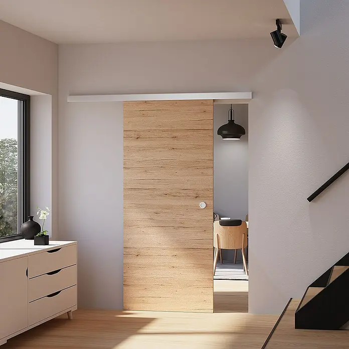 Inova Schiebetür-Komplettset Holz Komplettset Eiche San Remo mit Griffmuschel - 880 x 2.035 mm - Moderne Schiebetür aus Holz mit weißer Schiene in einem hellen Raum. Elegantes Design für ein stilvolles Zuhause.