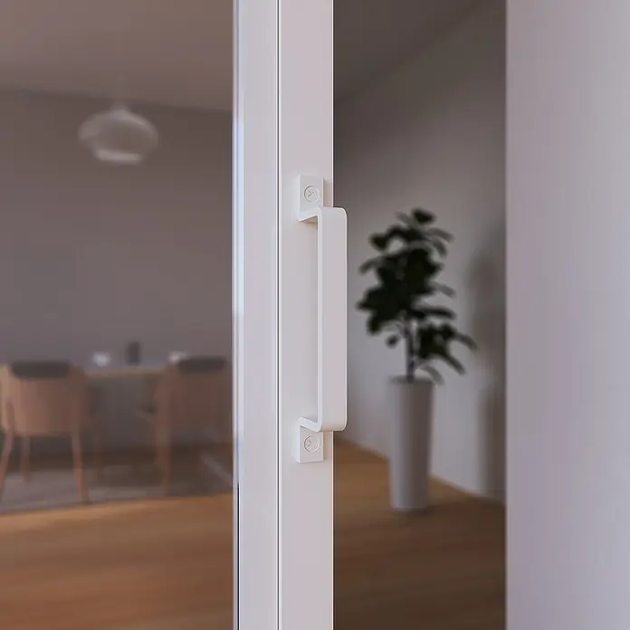 Inova Schiebetür-Komplettset Stahl Loft Klarglas Komplettset 6 Felder Kickplatte weiß inkl. Softclose -  - Nahaufnahme eines modernen, weißen Türgriffs, der Stil und Funktionalität vereint und das schlichte Design des Hauses ergänzt.