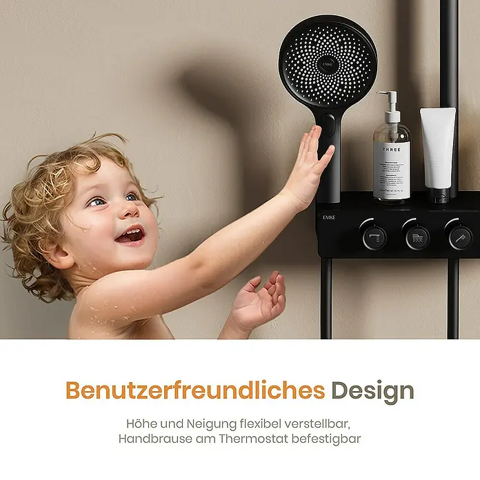 Emke Duschsystem Einstellbare Wassermenge F28 - Mit Thermostatarmatur, Lochabstand: 119 cm, Anzahl Strahlarten: 3 Stk., Schwarz - Ein Kind greift nach einer schwarzen Duschgarnitur mit Thermostat, die Shampoo und weitere Badezimmerutensilien hält.