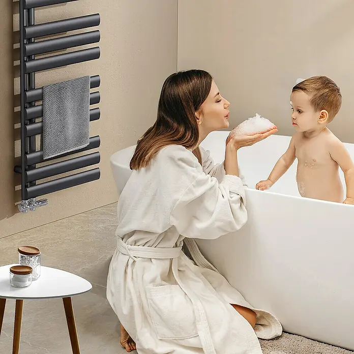 Emke Badheizkörper Elliptische Röhre Ignia SFTR4 - B x H: 40 x 143 cm, Anthrazit - Ein moderner, schwarzer Handtuchwärmer im Badezimmer mit einer Mutter und ihrem Kind, die ein Bad nehmen.