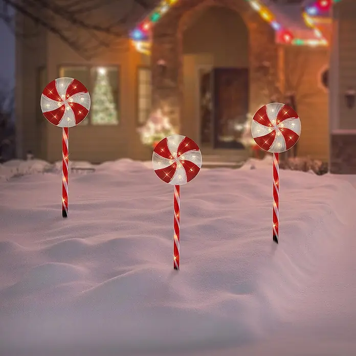 ECD Germany LED-Weihnachtsdekofigur Lollipop-Weihnachtsweg Weihnachten Lutscher Lichterkette Gartenleuchte - 300 x 18 x 62 cm, Rot, Weiß, Akkubetrieben, LED - Drei beleuchtete Zuckerstangen im Schnee vor einem Haus, eine festliche Dekoration für die Weihnachtszeit.