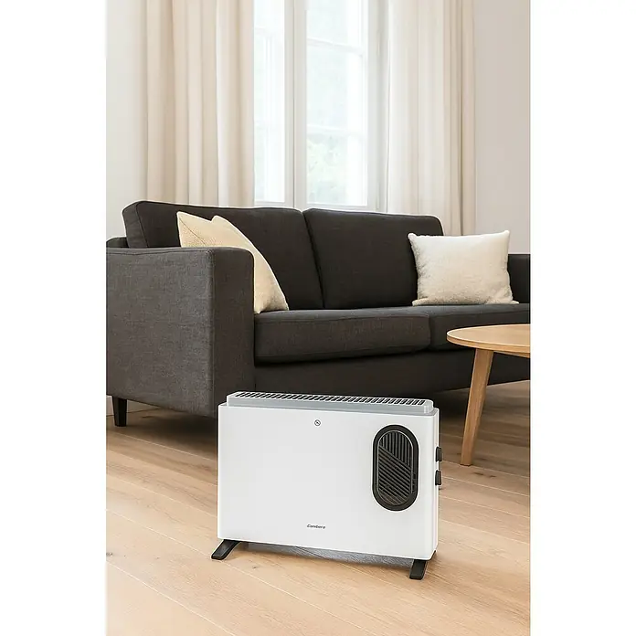 Corberó Convector de aire - 2.000 W, 18 x 53 x 15,3 cm, Blanco - Un radiador blanco Canberre está sobre un piso de madera clara en una sala de estar. Un sofá gris con cojines se puede ver al fondo.