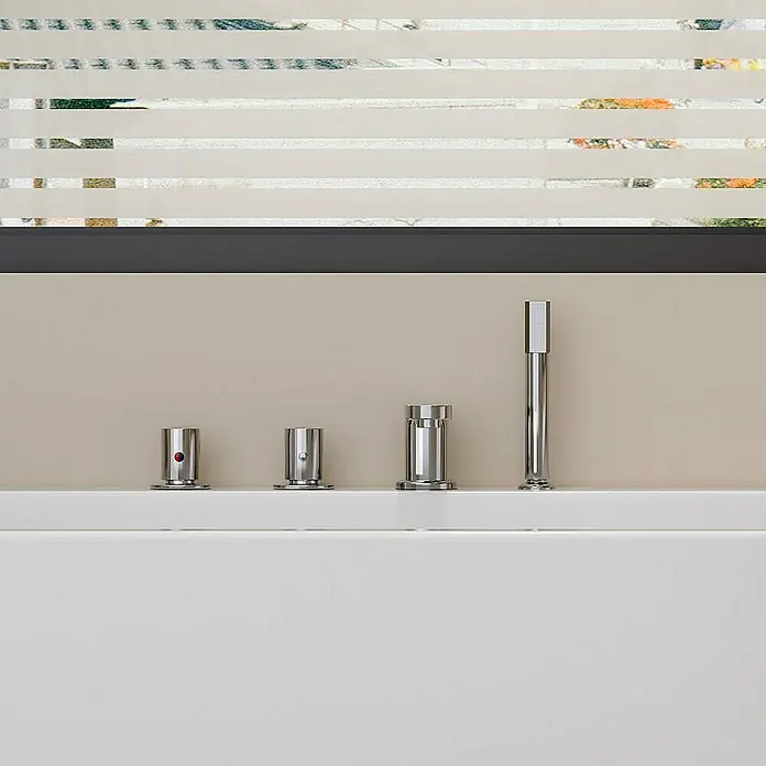 Home Deluxe Eckbadewanne AMBER - Weiß - Moderne Badewannenarmatur mit vier silbernen Bedienelementen auf einer weißen Oberfläche, vor beigem Hintergrund mit Fensterdekoration.