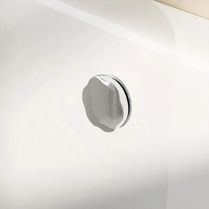 Home Deluxe Eckbadewanne ELARA -  - Nahaufnahme eines glänzenden, verchromten Badewannenablaufstopfens auf einer weißen Badewanne, der ein elegantes und modernes Design aufweist.