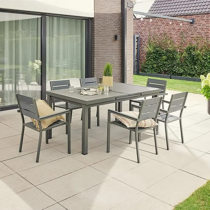 Home Deluxe Gartentisch-Set CALIDO MADERA - Tisch inkl. 6 Stühlen - Gesamtumfang: 6 -tlg., Ausziehbar - Ein stilvolles graues Gartenset mit Esstisch und sechs Stühlen auf einer hellen Terrasse, perfekt für Mahlzeiten im Freien.