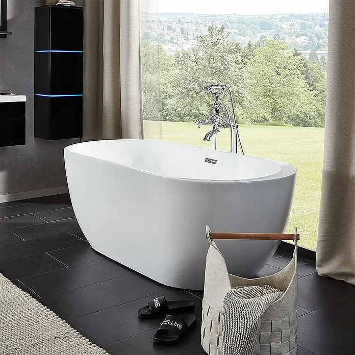 Home Deluxe Freistehende Badewanne CODO - Weiß - Freistehende Badewanne in einem modernen Badezimmer mit dunklen Fliesen und großen Fenstern mit Blick auf die Natur.