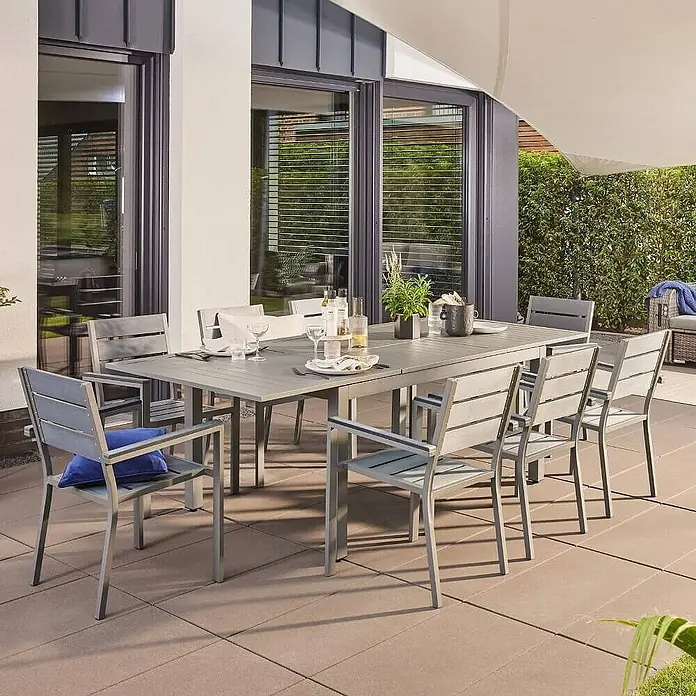 Home Deluxe Gartentisch-Set CASA - Gartentisch - Gesamtumfang: 1 -tlg., Ausziehbar - Ein graues Gartenset mit Tisch und Stühlen auf einer Terrasse mit Fliesen. Das Set bietet Platz für Mahlzeiten im Freien.