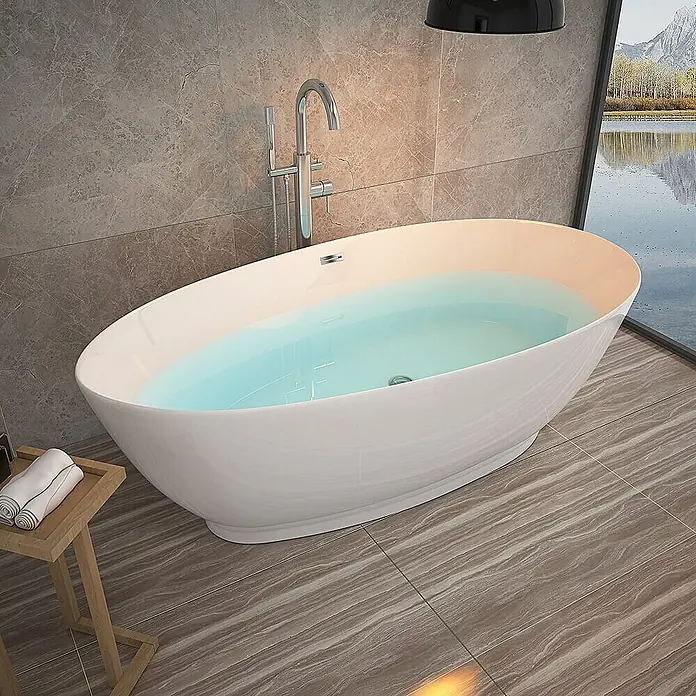 Home Deluxe Freistehende Badewanne DELIA - Weiß - Freistehende Badewanne mit Armatur und Handtüchern auf einem kleinen Tisch im Badezimmer mit Fenster und Fliesenboden.