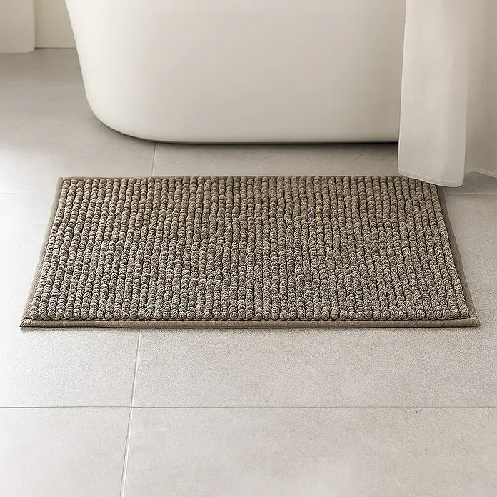 MSV Alfombra de baño Chenille - 60 x 40 cm, Poliéster, Gris - Alfombra de baño gris con textura nudosa colocada frente a una bañera sobre baldosas grises claras. La alfombra es rectangular y tiene un borde estrecho.