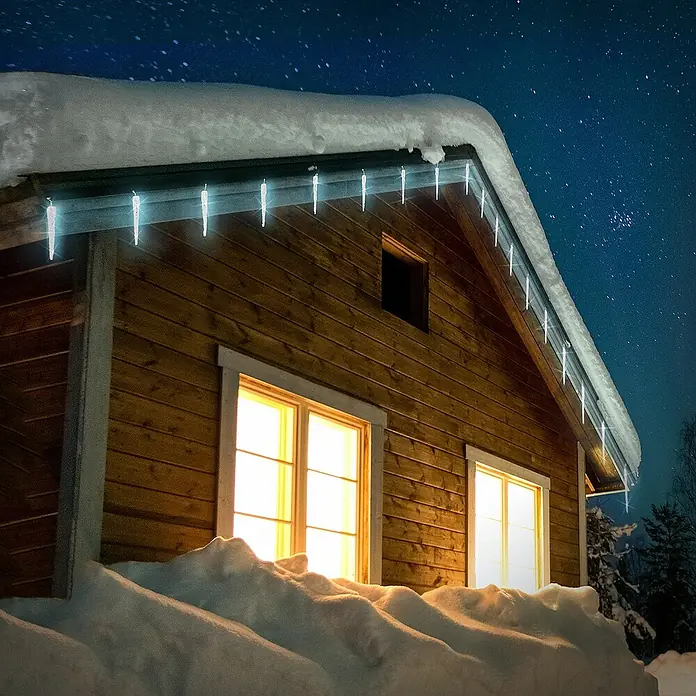 ECD Germany LED-Lichterkette - Außen, Lichtfarbe: Kaltweiß, Anzahl Leuchtmittel: 40 Stk., Netzbetrieben - Winterliche Hausansicht mit leuchtenden Eiszapfenlichtern am Dachrand, die eine warme Atmosphäre in der kalten Nacht schaffen.