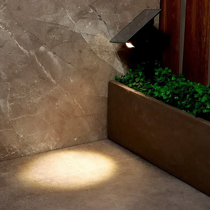 Arte confort Lámpara con pica Haloz - 2 W, Blanco cálido - Una luz solar ilumina una esquina. La luz solar está montada en una pared y proyecta luz sobre el suelo.