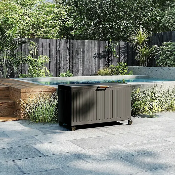 Kissenbox Mirador Life - L x B x H: 130 x 60,4 x 70 cm, Metall, Anthrazit - Eine graue, rollbare Aufbewahrungsbox mit Holzgriff steht auf einer Terrasse, ideal zur Poolaufbewahrung im Außenbereich.