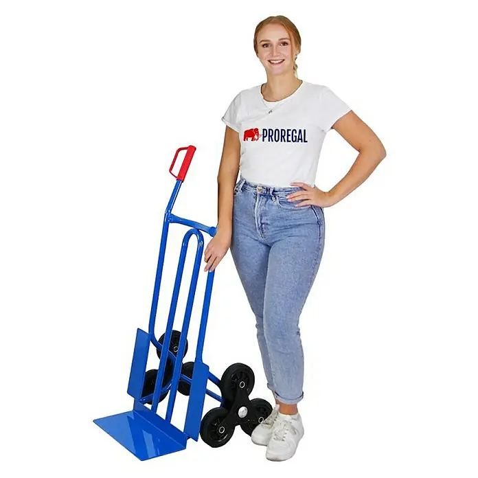 Proregal Treppen-Sackkarre RHINO mit XL Schaufel, 250 kg Traglast & Vollgummibereifung - Stahl, Traglast: 250 kg - Die Frau steht neben einem blauen Treppensteiger mit sechs Rädern und rotem Griff. Ideal zum einfachen Transport schwerer Gegenstände über Treppen.