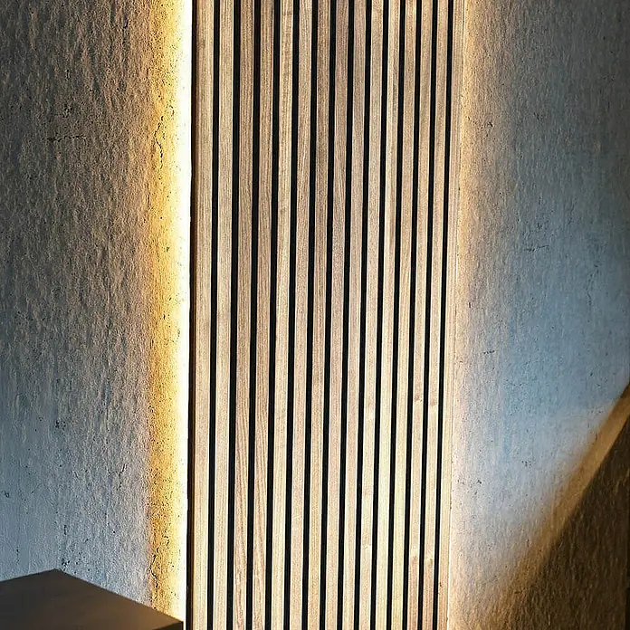 Home Deluxe Akustikpaneel SONIC Light Oak - H 240 x B 40 x T 2,1 cm - Light Oak, L x B x S: 240 cm x 2,1 cm x 21 mm, 1 Stk., 0,97 m² - Nahaufnahme einer Akustikwand aus Holzlatten, die an einer Wand mit stimmungsvoller Beleuchtung angebracht ist und eine moderne Ästhetik erzeugt.