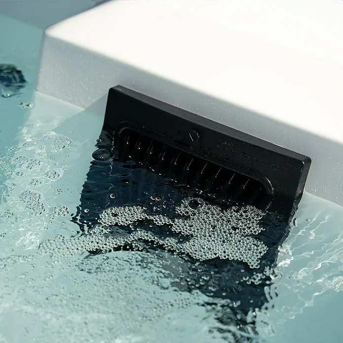 Home Deluxe Außen-Whirlpool NIMBUS DELUXE inkl. Treppe und Thermoabdeckung - Weiß, Max. Personenzahl: 2 Stk. - Nahaufnahme eines schwarzen Skimmers in einem Whirlpool, umgeben von Blasen, der für sauberes Wasser sorgt.