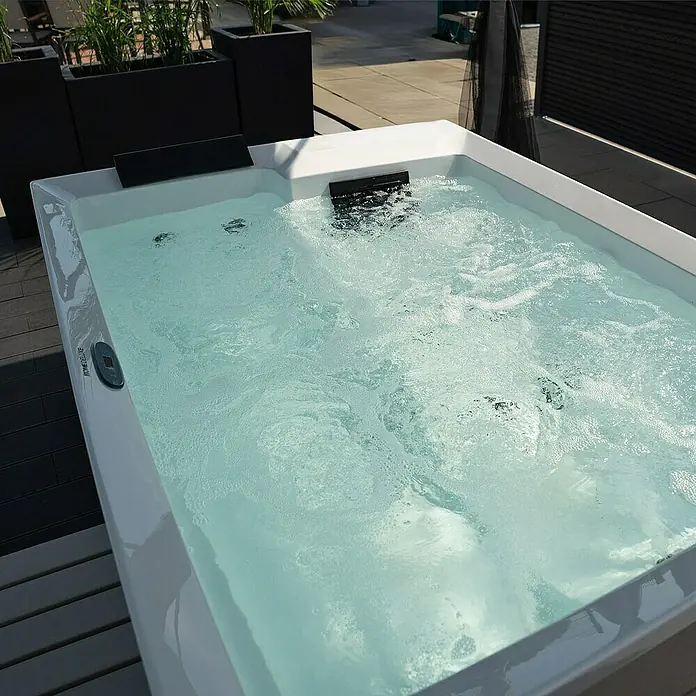 Home Deluxe Außen-Whirlpool NIMBUS DELUXE inkl. Treppe und Thermoabdeckung - Weiß, Max. Personenzahl: 2 Stk. - Nahaufnahme eines sprudelnden, rechteckigen Whirlpools, der in einem modernen Außenbereich für Entspannung und Wellness steht.