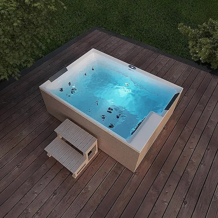 Home Deluxe Außen-Whirlpool NIMBUS DELUXE inkl. Treppe und Thermoabdeckung - Weiß, Max. Personenzahl: 2 Stk. - Das Bild zeigt einen modernen Whirlpool mit Treppe, eingebettet in eine Holzterrasse und umgeben von grüner Natur.
