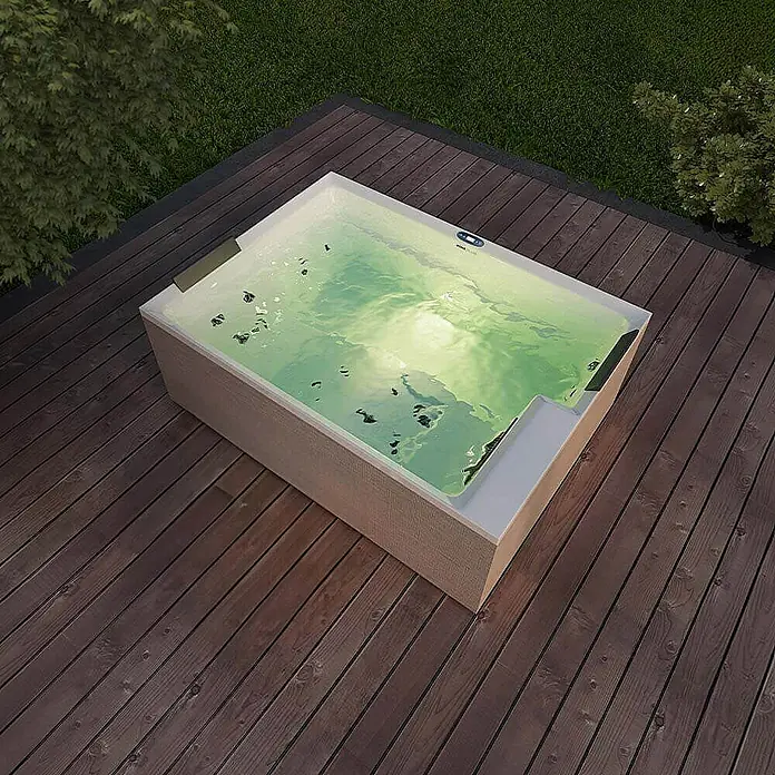Home Deluxe Außen-Whirlpool NIMBUS DELUXE PURE - 190 x 140 x 70 cm, Weiß, Max. Personenzahl: 2 Stk. - Rechteckiger Whirlpool mit Wasser auf einer Holzterrasse, umgeben von üppigem Grün. Entspannung pur mit diesem stilvollen Außenbereich.