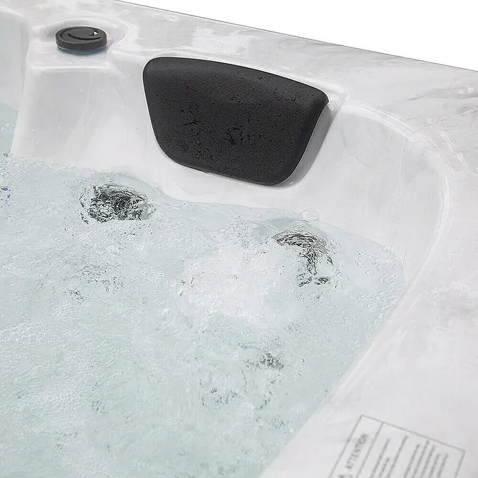 Home Deluxe Outdoor Whirlpool WHITE MARBLE Mit Treppe und Thermoabdeckung -  - Nahaufnahme eines Whirlpools mit einem schwarzen Nackenkissen und sprudelndem Wasser, das Entspannung verspricht.