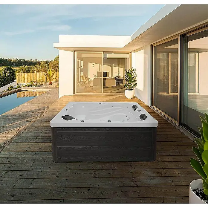 Home Deluxe Außen-Whirlpool SUNSET PURE - Anthrazit, Max. Personenzahl: 3 Stk. - Ein luxuriöser Whirlpool auf einer Holzterrasse, ideal zum Entspannen im Freien. Das moderne Design fügt sich nahtlos in die stilvolle Umgebung ein.