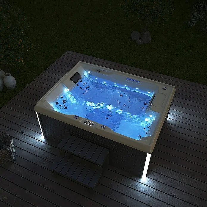 Home Deluxe Außen-Whirlpool STREAM inkl. Treppe und Thermoabdeckung - Anthrazit, Max. Personenzahl: 3 Stk. - Ein beleuchteter Whirlpool auf einer Holzterrasse sorgt für eine entspannende Atmosphäre. Der Pool strahlt mit blauem Licht und lädt zum Verweilen ein.