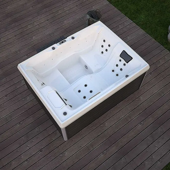 Home Deluxe Außen-Whirlpool STREAM inkl. Treppe und Thermoabdeckung - Anthrazit, Max. Personenzahl: 3 Stk. - Ein rechteckiger Whirlpool mit grauem Gehäuse und weißem Becken, der auf einer Holzterrasse steht, lädt zum Entspannen ein.
