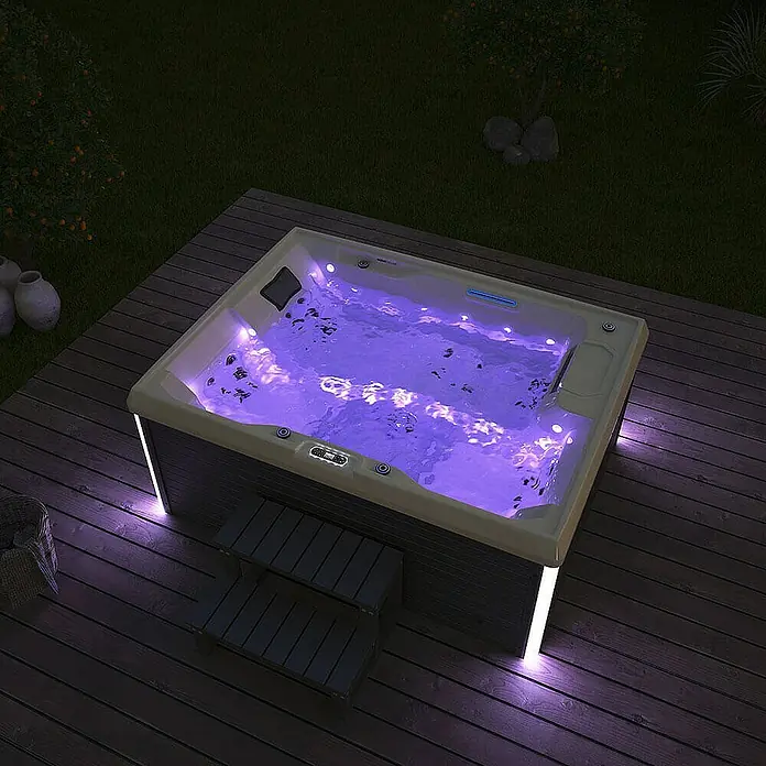 Home Deluxe Außen-Whirlpool STREAM inkl. Treppe und Thermoabdeckung - Anthrazit, Max. Personenzahl: 3 Stk. - Ein luxuriöser Whirlpool mit violetter Beleuchtung, eingebettet in eine Holzterrasse, lädt zum Entspannen im Freien ein.