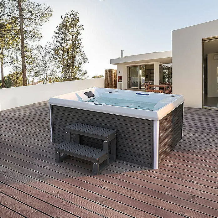 Home Deluxe Außen-Whirlpool STREAM inkl. Treppe und Thermoabdeckung - Anthrazit, Max. Personenzahl: 3 Stk. - Ein luxuriöser Whirlpool mit Treppe steht auf einer Holzterrasse, ideal zum Entspannen im Freien.