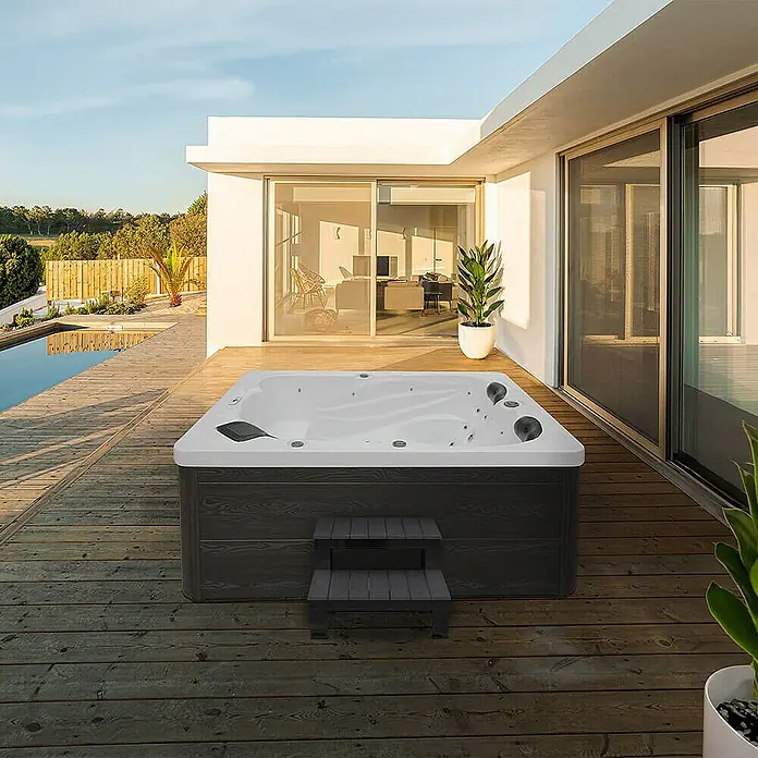 Home Deluxe Außen-Whirlpool SUNSET inkl. Treppe und Thermoabdeckung - Weiß, Max. Personenzahl: 3 Stk. - Ein luxuriöser Whirlpool im Freien mit Treppe und modernem Design, eingebettet in eine stilvolle Terrassenumgebung mit Poolblick.