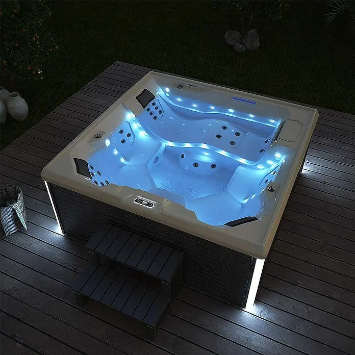 Home Deluxe Außen-Whirlpool STREAM BIG PURE - Anthrazit, Max. Personenzahl: 5 Stk. - Ein luxuriöser Whirlpool mit blauer Beleuchtung, eingebettet in eine Holzterrasse, lädt zum Entspannen im Freien ein.