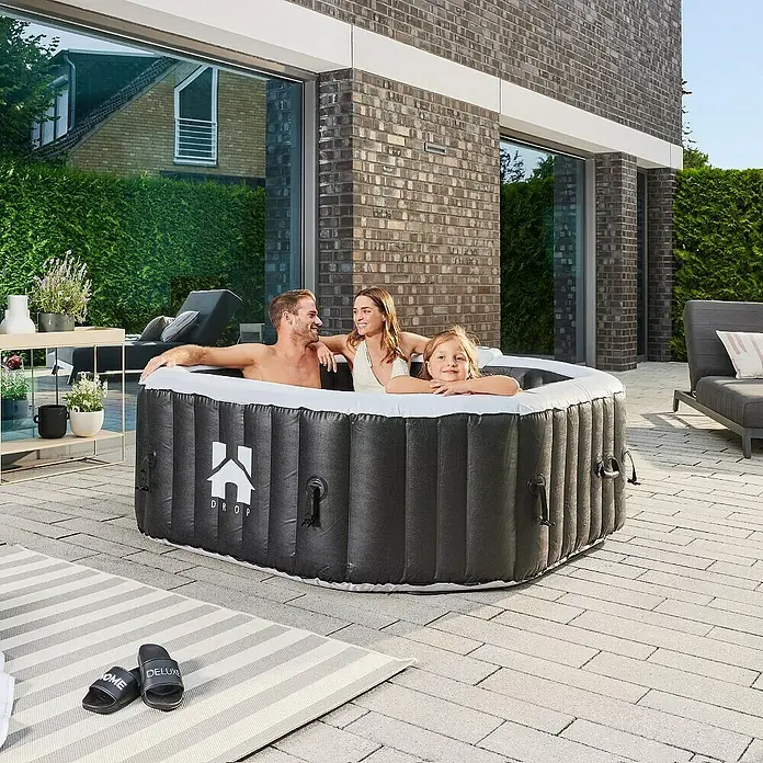 Home Deluxe Außen-Whirlpool DROP inkl. Kissen, Getränkehalter und Sonnendach - 185 x 185 x 65 cm, Schwarz, Max. Personenzahl: 6 Stk. - Aufblasbarer Whirlpool DROP mit Familie im Garten. Der graue Pool bietet Platz für Entspannung im Freien und verspricht erholsame Stunden.
