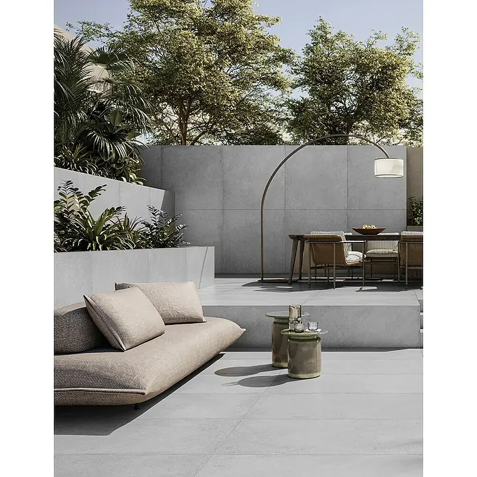 Terrassenfliese Moonstone White - 60 x 120 x 2 cm, Weiß, Matt - Außenbereich mit modernem Sofa, Tisch und Stehlampe vor einer grauen Wand. Elegantes Design für Terrasse oder Garten.