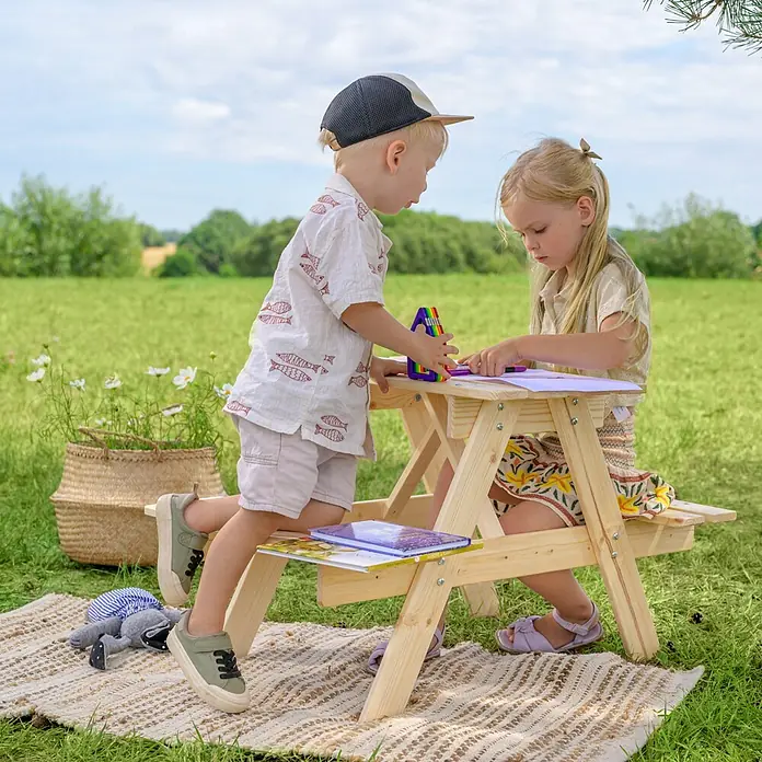 Timbela Kinder-Picknicktisch - 81 x 60 x 50 cm, Holz, Ohne Staufach - Kinder spielen am Kindersitzgarnitur Picknicktisch im Freien, mit Büchern und Stiften. Der Tisch ist aus hellem Holz gefertigt.