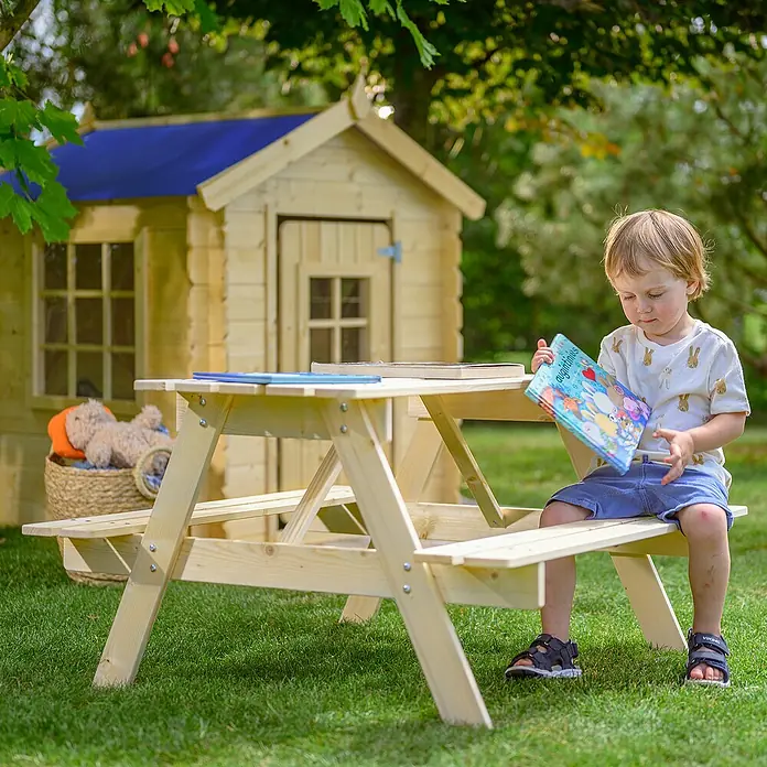 Timbela Kinder-Sitzgruppen-Set - 90 x 90 x 50 cm, Holz, Ohne Staufach - Ein heller Holz-Kindersitzgarnitur steht im Garten, auf dem ein kleiner Junge sitzt und ein Buch liest.