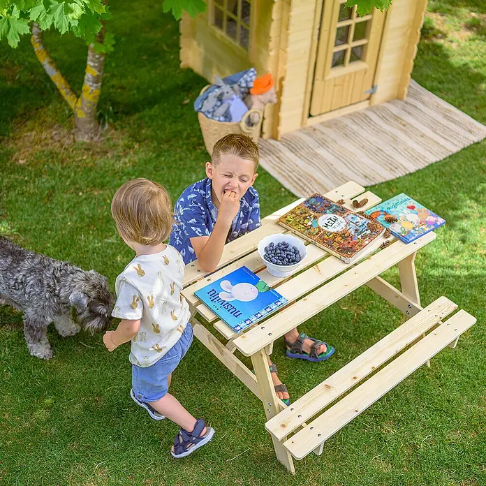 Timbela Kinder-Sitzgruppen-Set - 90 x 90 x 50 cm, Holz, Ohne Staufach - Ein helles Holz Kindertisch mit Bänken steht im Garten, perfekt zum Spielen und Essen im Freien.