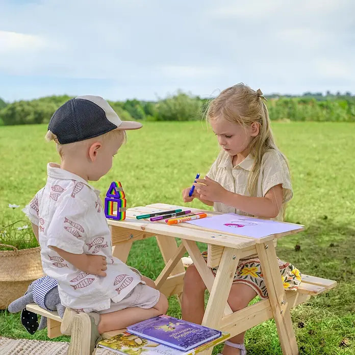 Timbela Kinder-Picknicktisch - 81 x 60 x 50 cm, Holz, Ohne Staufach - Kinder sitzen an einem kleinen Picknicktisch aus Holz und malen mit bunten Stiften auf Papier. Ideal für kreative Spiele im Freien.