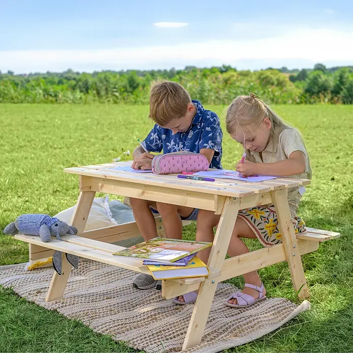 Timbela Kinder-Sitzgruppen-Set - 90 x 90 x 50 cm, Holz, Mit Staufach - Kinder sitzen an einem hellen Picknicktisch im Freien und malen. Der Tisch ist aus Holz und steht auf einem Teppich im Grünen.