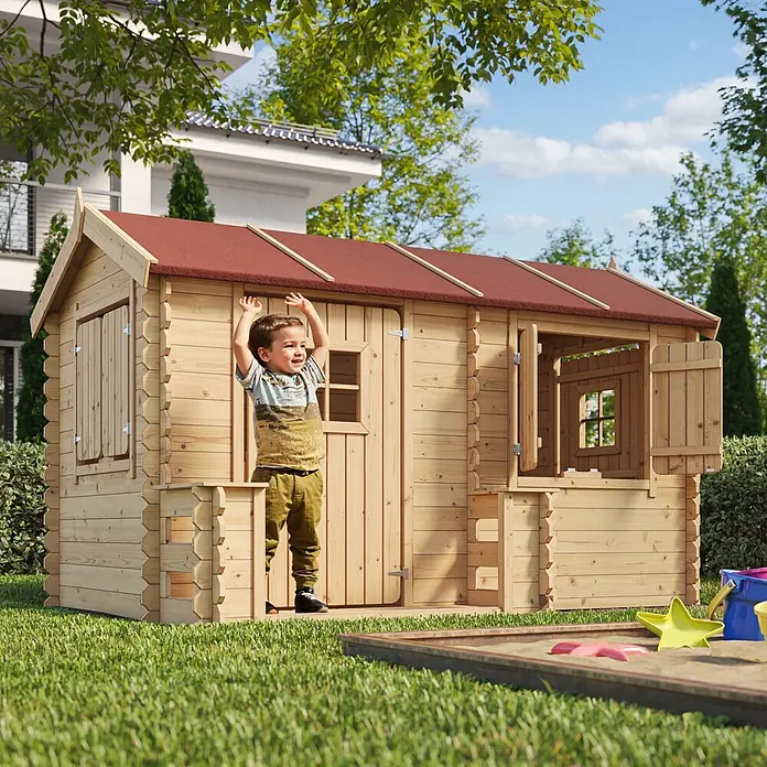 Timbela Spielhaus - L x B x H: 146 x 241 x 151 cm, Holz, Natur - Ein Junge spielt vor einem hölzernen Kinderspielhaus mit rotem Dach im Garten.