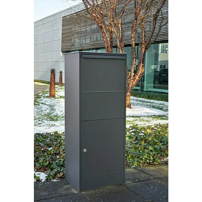 Allux Paketbox 800 Large - L x B x H: 320 x 450 x 115 mm, Anthrazit, Stahl, Paketfach - Moderner, anthrazitfarbener Briefkasten mit mehreren Fächern vor einem Gebäude mit Bäumen und Schnee. Ideal für den stilvollen Empfang von Post.